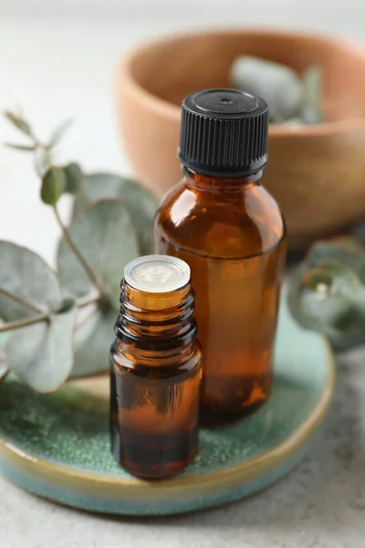 Flaschen Mit Ätherischem Eukalyptusöl Und Pflanzenzweigen Auf Hellgrauem Tisch — Stockfoto