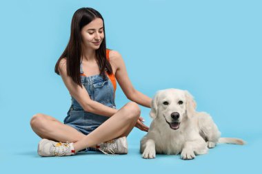 Açık mavi arka planda şirin Labrador Retriever köpeği olan mutlu bir kadın. Sevimli hayvan.