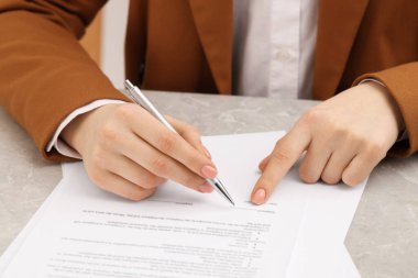 Woman signing document at table, closeup view