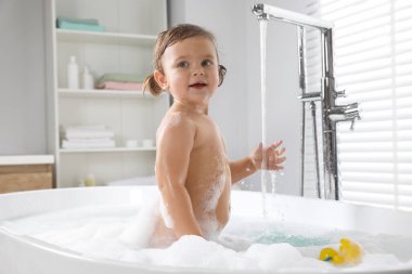 Evde köpüklü banyo yapan tatlı küçük kız.