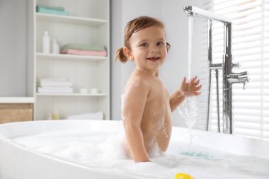 Evde köpüklü banyo yapan tatlı küçük kız.