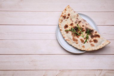 Açık ahşap masa üzerinde leziz bir calzone tabağı, üst manzara. Metin için boşluk