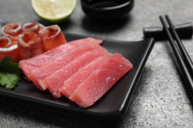 Sashimi seti (çiğ ton balığı ve somon dilimleri) ve maydanozlu gri masa, yakın plan.