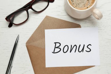 Kahverengi zarf, içinde Bonus, kalem, gözlük ve kahve olan mektup beyaz ahşap masa, düz yatıyordu.