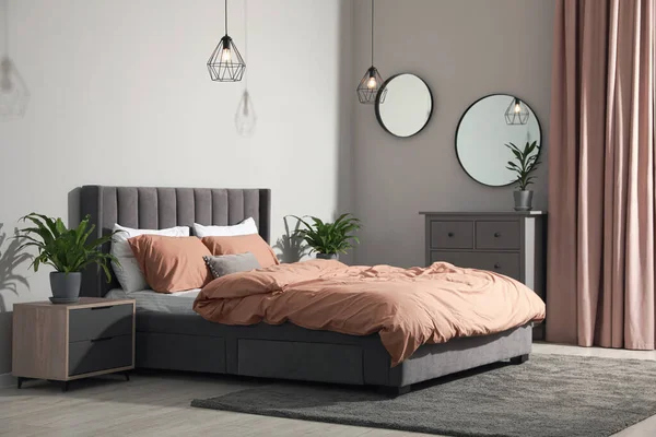 快適なベッドと緑の観葉植物とスタイリッシュなベッドルームのインテリア — ストック写真
