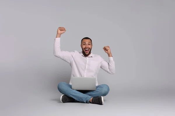 灰色の背景にノートパソコンを持つ幸せな若い男 テキストのためのスペース — ストック写真