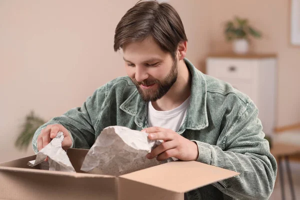 stock image Happy man opening parcel at home. Internet shopping