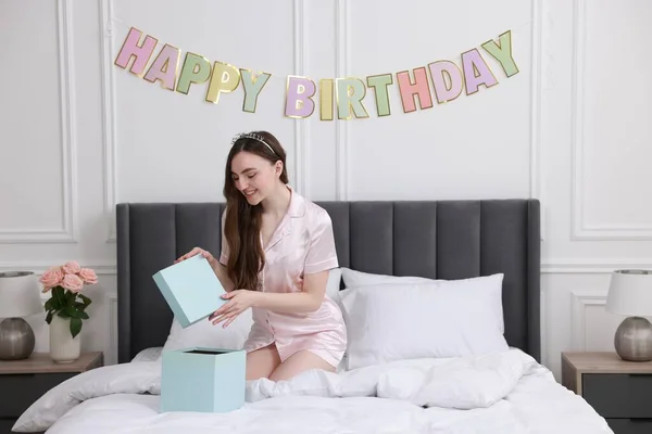 漂亮的年轻女人 带着头巾打开礼品盒躺在床上的房间里 生日快乐 — 图库照片