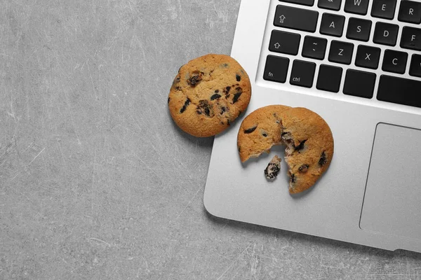 Chocolate chip cookies and laptop on light grey table, flat lay. Space for text