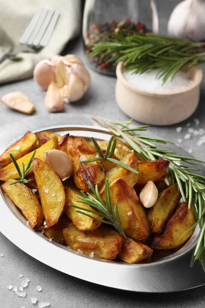 美味的烤土豆和芬芳的迷迭香放在灰色质感桌子上 — 图库照片