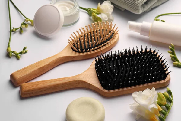 stock image Wooden hairbrushes, different cosmetic products and beautiful flowers on white background