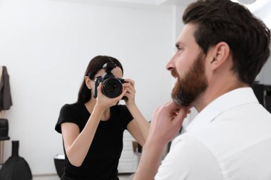 Professional photographer working with handsome model in modern photo studio