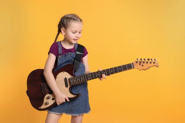 Turuncu arka planda elektro gitarı olan tatlı bir kız.