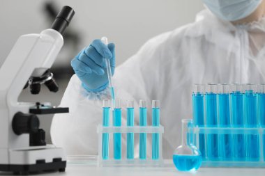 Laboratuvarda test tüpüne numune damlatan bir bilim adamı.
