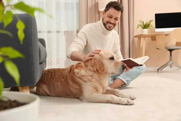 男人在自家可爱的拉布拉多猎犬附近的地板上看书 — 图库照片