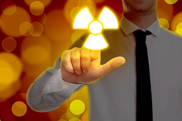 ぼやけた光と赤の背景にデジタル画面上の輝く放射線警告シンボルに触れる男は クローズアップ — ストック写真