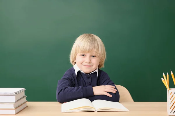 幸せな小さな学校の子供は机の上に座って本近くの黒板 — ストック写真