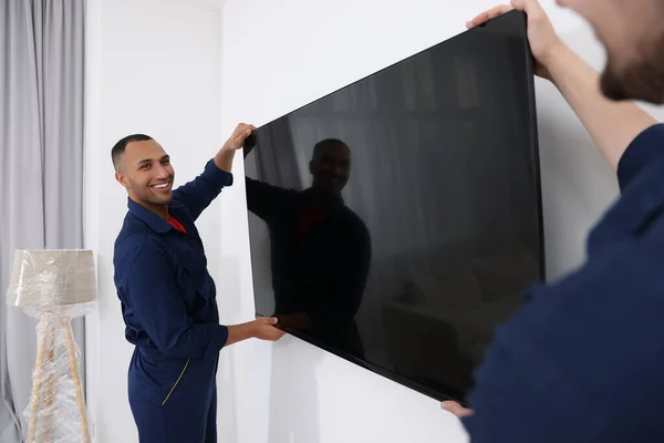 Male movers carrying plasma TV in new house