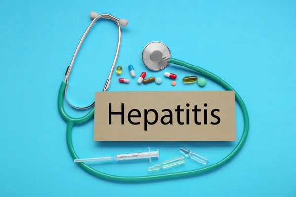 stock image Cardboard with word Hepatitis and medical supplies on light blue background, flat lay