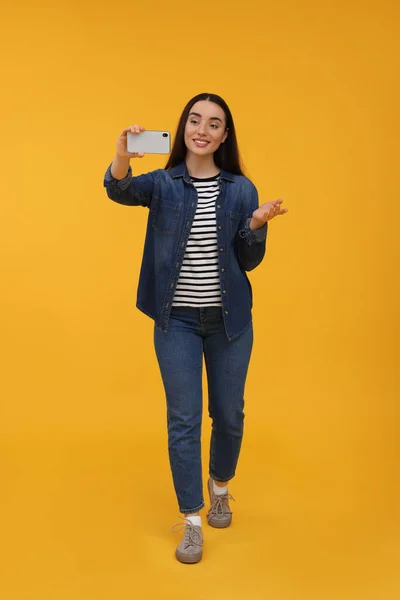 Uśmiechnięta Młoda Kobieta Robi Selfie Smartfonem Żółtym Tle — Zdjęcie stockowe