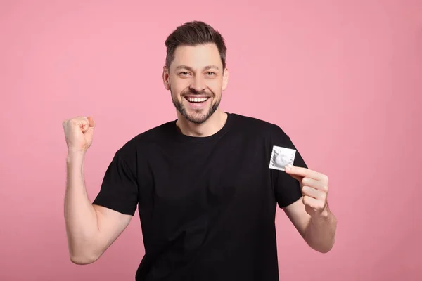 Excited Man Holding Condom Pink Background — Stock Photo, Image