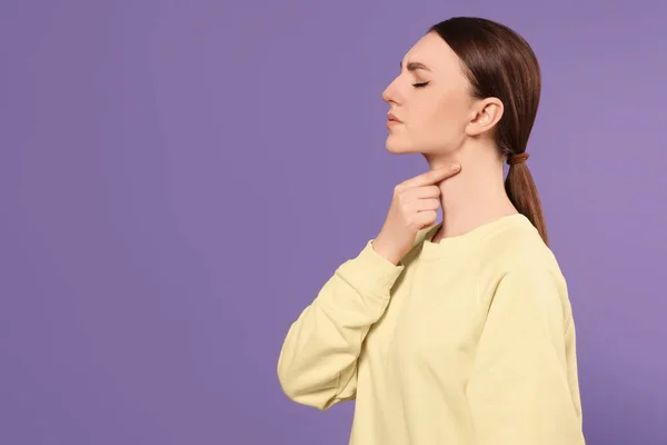 stock image Young woman with sore throat on violet background. Space for text