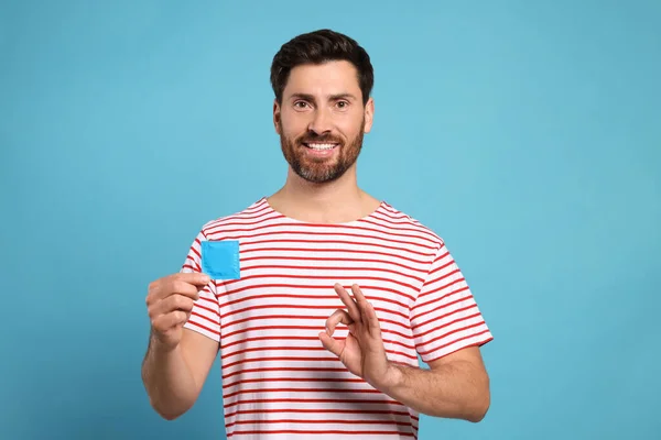 Homem Feliz Com Preservativo Mostrando Gesto Fundo Azul Claro Sexo — Fotografia de Stock