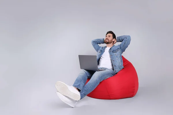 Homem Feliz Com Laptop Sentado Cadeira Beanbag Contra Fundo Cinza — Fotografia de Stock