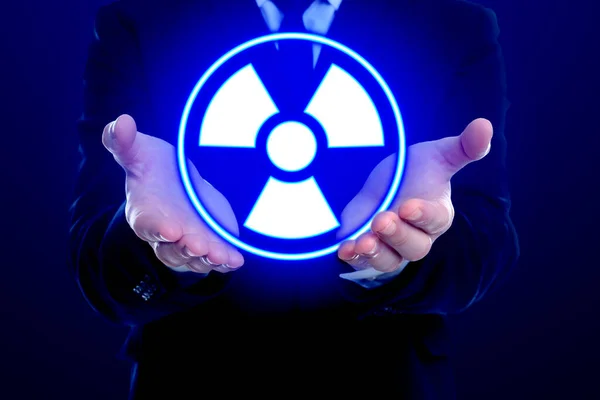 暗い青の背景に輝く放射線警告のシンボルを持っている男 クローズアップ — ストック写真