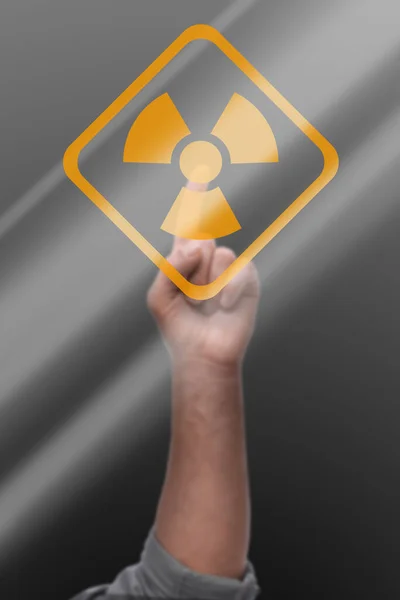 灰色の背景にデジタル画面上の放射線警告シンボルに触れる男 クローズアップ — ストック写真