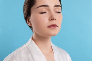 Portrait of attractive young woman with smooth skin on turquoise background