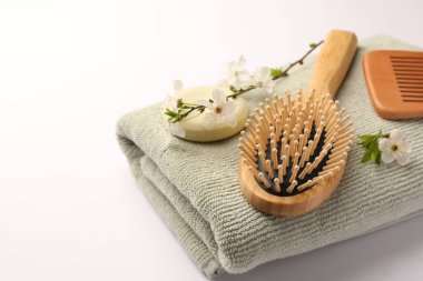 Tahta saç fırçası, sağlam şampuan, tarak, havlu ve beyaz arka planda çiçekli dallar. Metin için boşluk, kapatma.