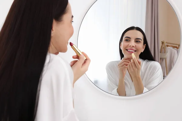 Vacker Ung Kvinna Som Applicerar Läppstift Nära Spegeln Inomhus — Stockfoto