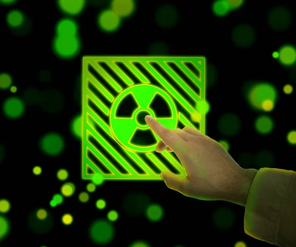 男人用模糊的绿色和黄色灯在黑色背景上触摸发光的辐射警告标志 — 图库照片