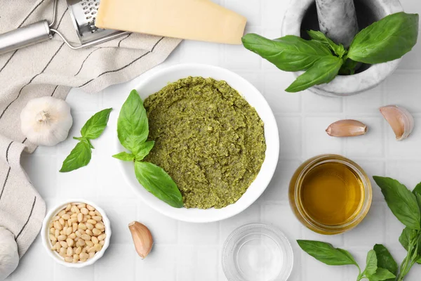 stock image Tasty pesto sauce and ingredients on white tiled table, flat lay