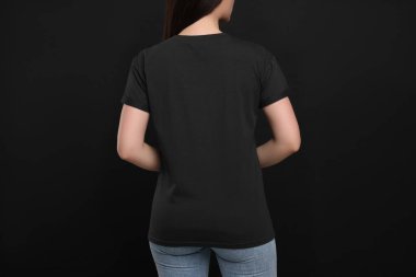 Woman wearing black t-shirt on dark background, back view clipart