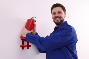 Üniformalı adam yangın söndürücüyü içeride kontrol ediyor.