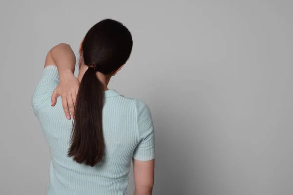 薄い灰色の背景に背中の痛みに苦しんでいる若い女性 テキストのためのスペース 関節炎の症状 — ストック写真