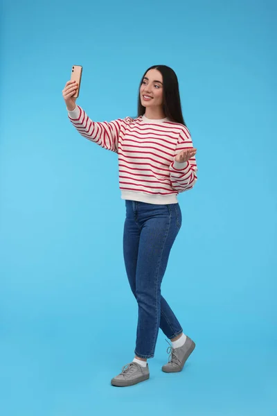 Lächelnde Junge Frau Macht Selfie Mit Smartphone Auf Hellblauem Hintergrund — Stockfoto