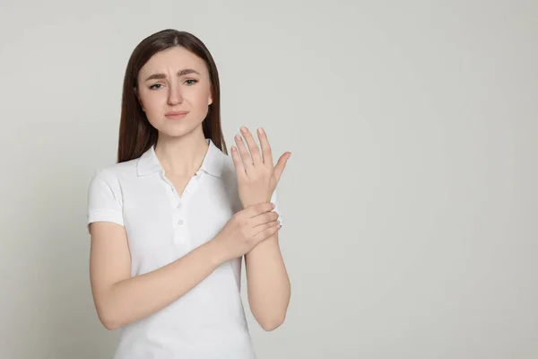 薄い灰色の背景 テキストのためのスペースに彼女の手の痛みに苦しんでいる若い女性 関節炎の症状 — ストック写真