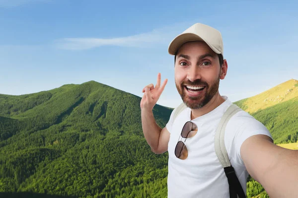 Χαμογελαστός Άντρας Βγάζει Σέλφι Και Δείχνει Σημάδι Ειρήνης Στα Βουνά — Φωτογραφία Αρχείου
