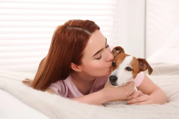女性接吻かわいいですジャックRussell Terier犬オンベッドにホーム — ストック写真
