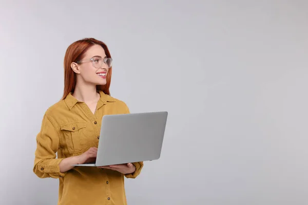 グレーの背景にノートパソコンで働く若い女性の笑顔 テキストのためのスペース — ストック写真