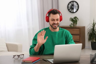 Kulaklıklı adam evde dizüstü bilgisayarda çalışıyor. Çevrimiçi çeviri kursu