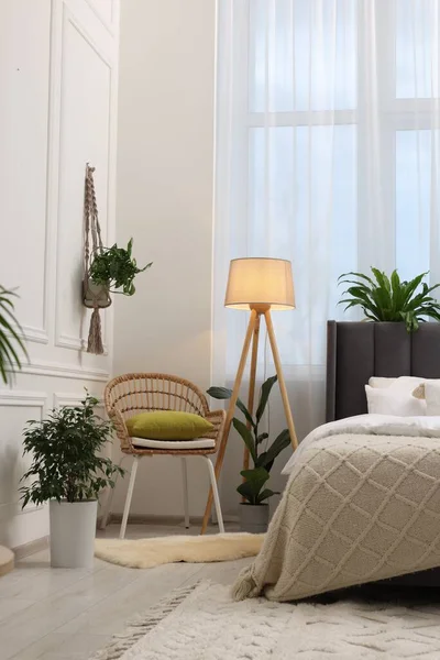 快適なベッド ランプ ウィッカーアームチェア ベッドルームの美しい観葉植物 インテリアデザイン — ストック写真