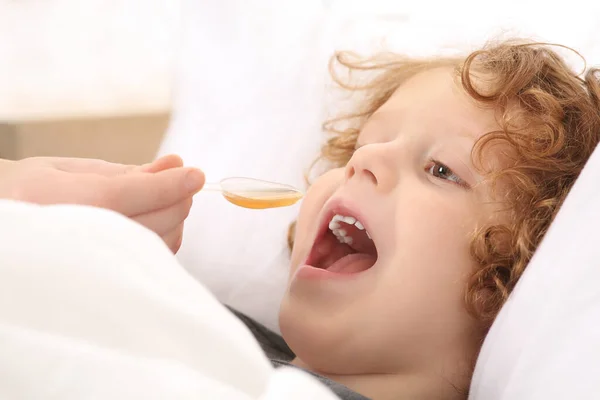 stock image Mother giving cough syrup to her son on bed, closeup