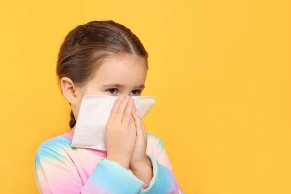女孩在橙色背景下的组织吹鼻涕 文字空间 感冒症状 — 图库照片