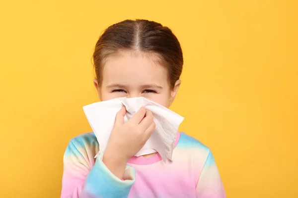 女孩在橙色背景下的组织里吹鼻涕 感冒症状 — 图库照片