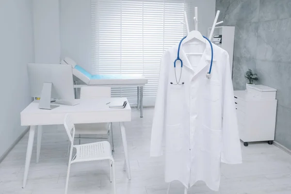 Λευκό Φόρεμα Γιατρού Και Στηθοσκόπιο Που Κρέμονται Στο Ράφι Στην — Φωτογραφία Αρχείου