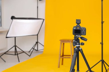 Kamera tripoda, bar taburesi ve profesyonel ışıklandırma ekipmanları modern fotoğraf stüdyosunda, metin için yer